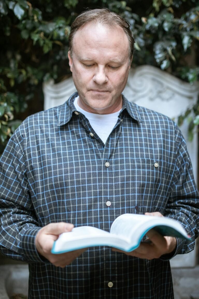 Man in Blue and White Checkered Dress Shirt Reading Book